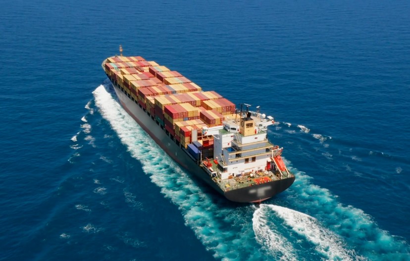 A large container ship cuts through the cerulean water