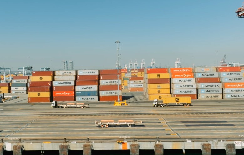 A large container ship loaded with colorful cargo containers floats in the water